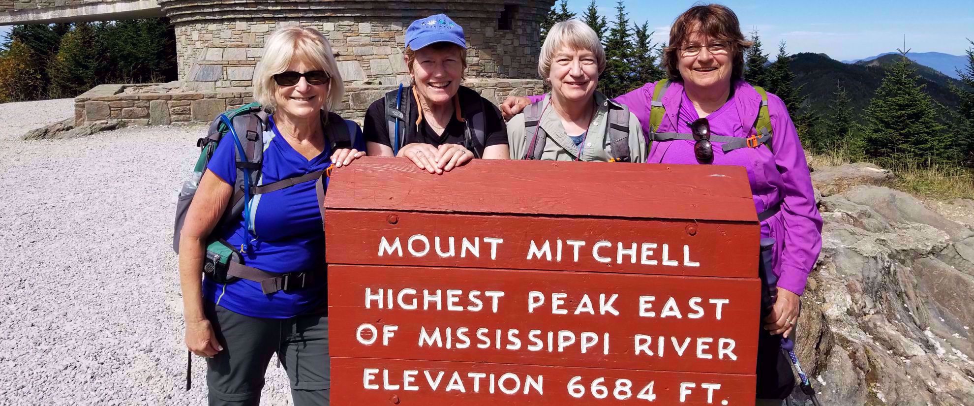 Picture of Blue Ridge Rambling Group women's travel standing by mount mitchell sign