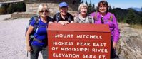 Picture of Blue Ridge Rambling Group women's travel standing by mount mitchell sign