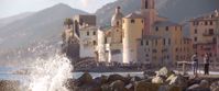 Waves crashing on rocks in italy with old building in background