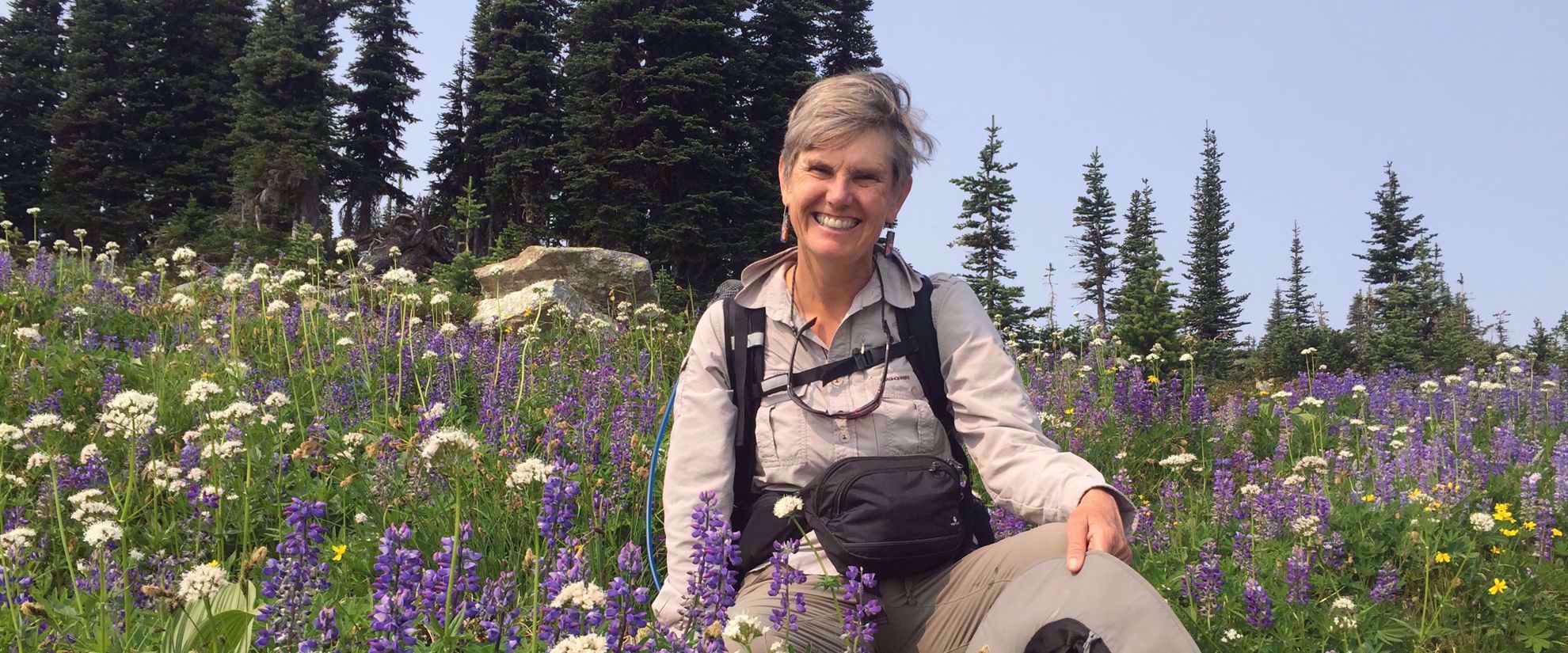 Picture of Hiking Hut to Hut in British Columbia woman smiles in wildflower field in bc canada