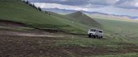 white tour bus driving up mountain in mongolia
