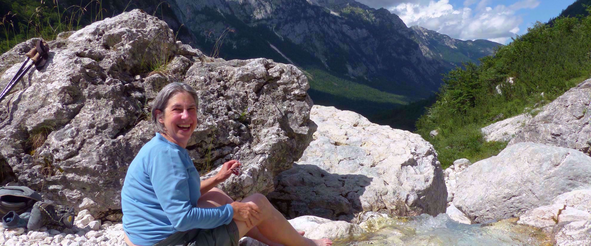 woman laughs dips feet in cold water slovenia