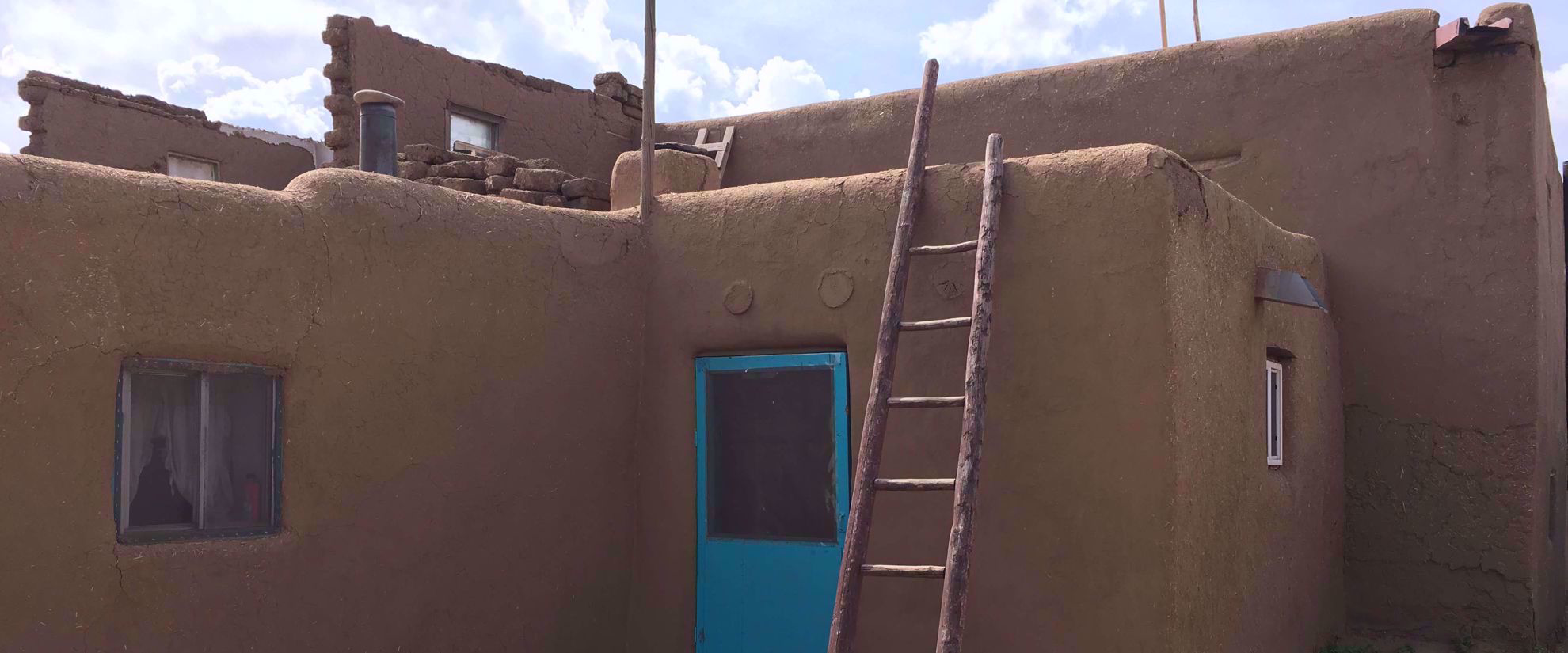 ladder and blue door on clay house in santa fe