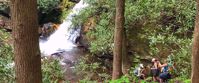 Picture of Waterfalls, Wildflowers, and Wineries women hiking down to waterfall surrounded by greenery