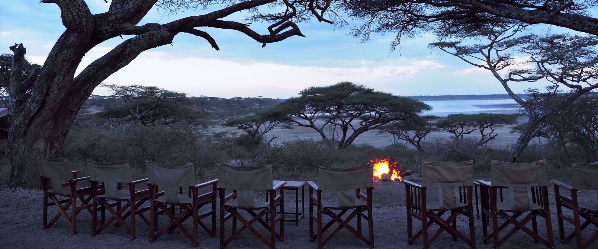 chairs on plains of tanzania in front of fire
