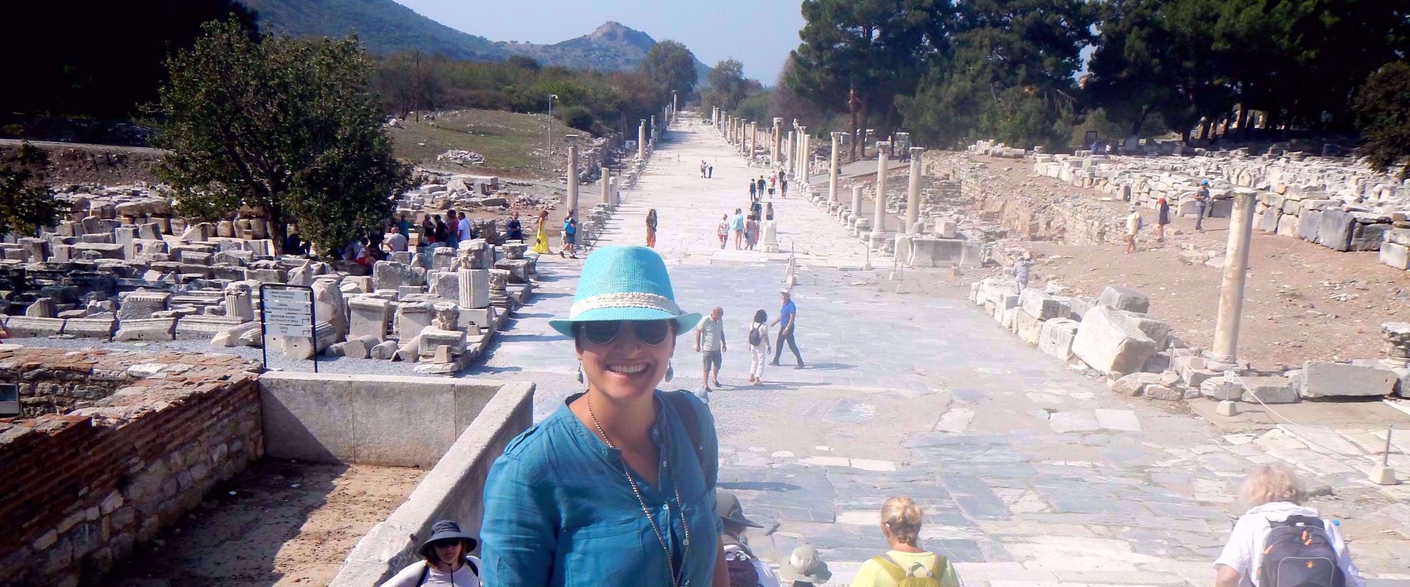 woman on group tour smiles for photo in turkish ruins