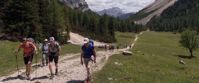 women hike on path through northern italian alps on group adventure tour
