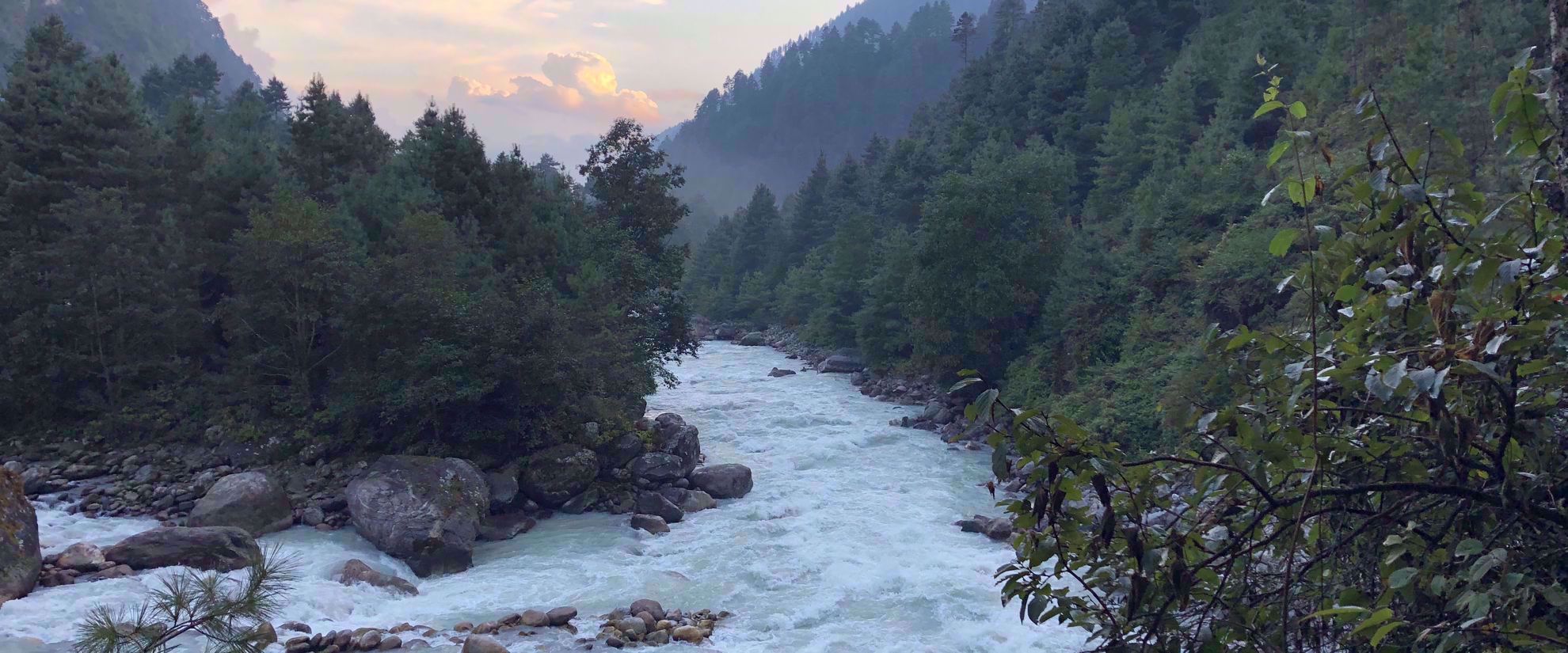 fast moving river in nepal with boulders and trees