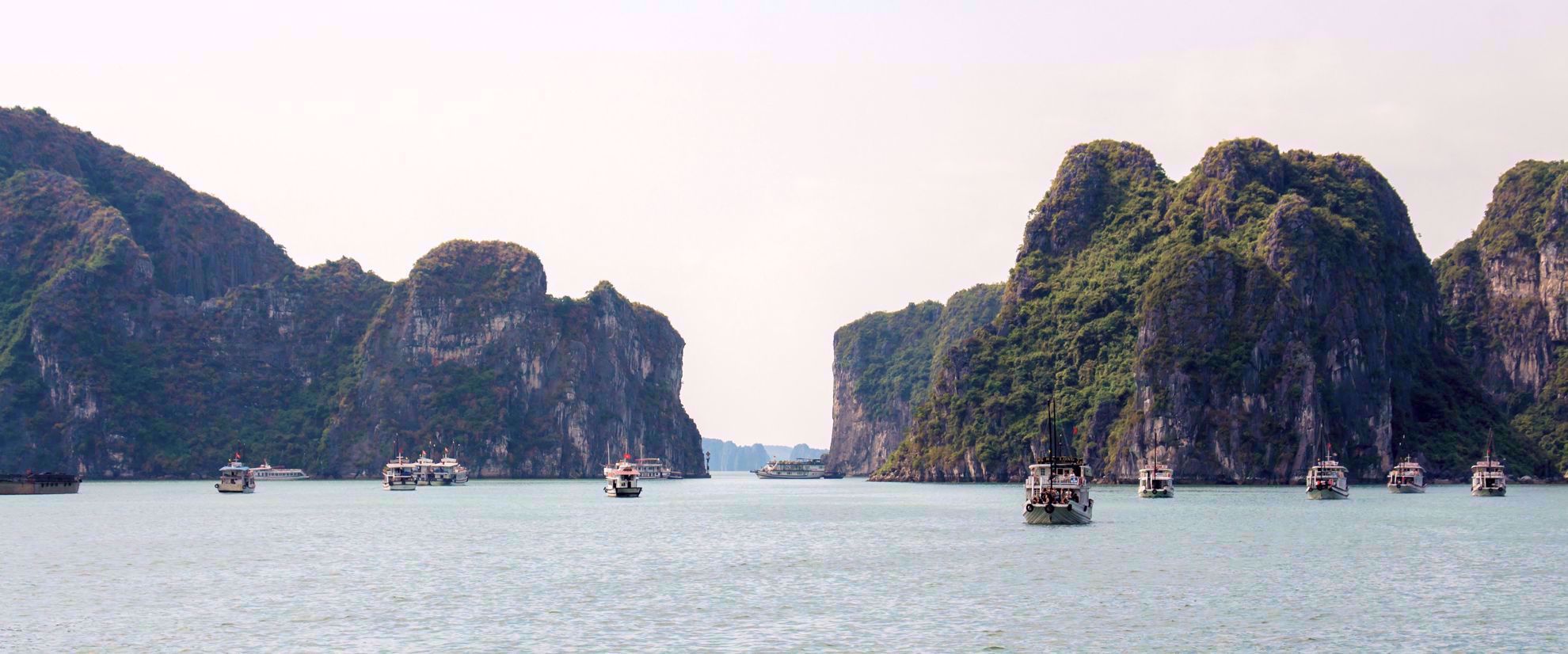 landscape of boats in vietnam with green mountain spires