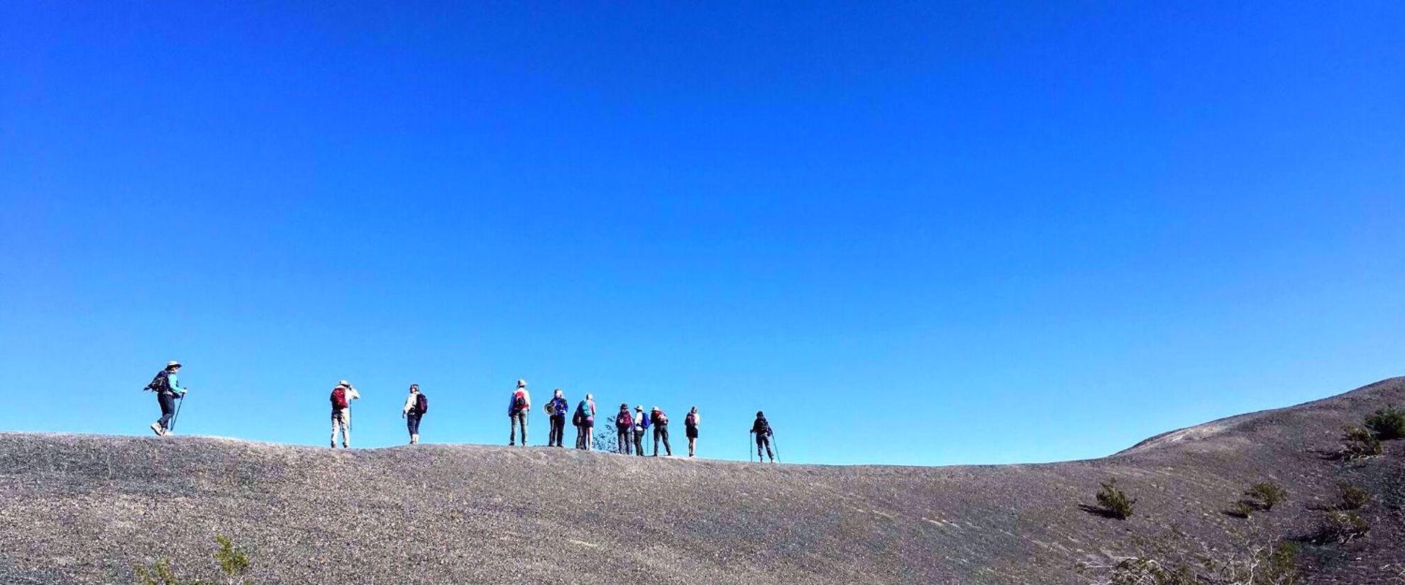 Picture of Death Valley Delights women on a hike on a ridge desert photo. bright blue sky in background