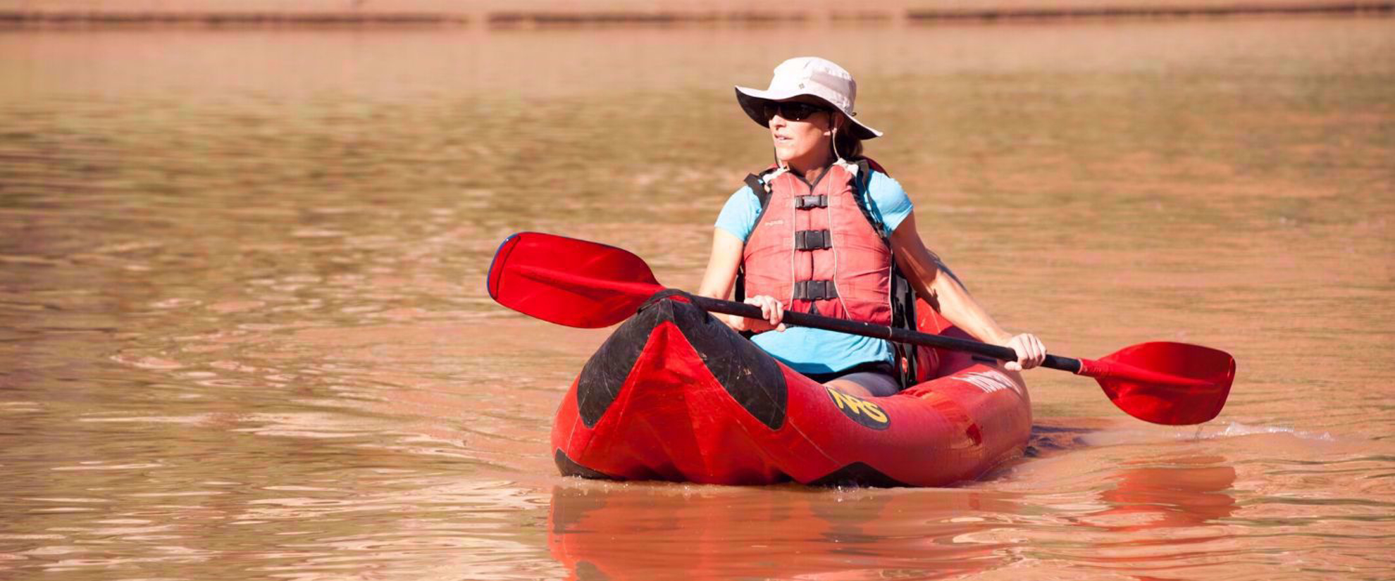 Solo woman paddling in river on Cataract Canyon. Colorado River