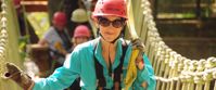 Picture of Blue Ridge Rambling Woman crossing suspension bridge, smiling with red helmet