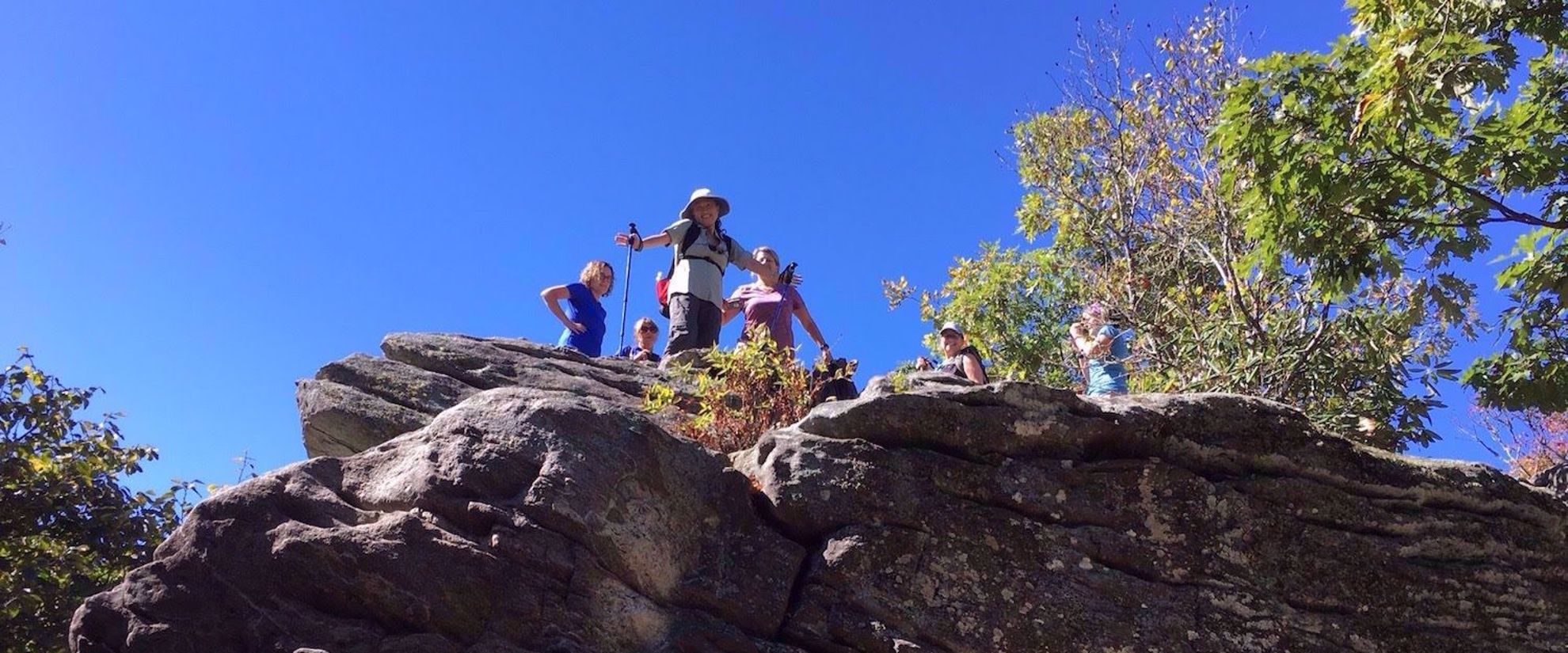 Picture of Appalachian Autumn Adventures Women hiking Appalachian trail, standing on rock looking down and smiling